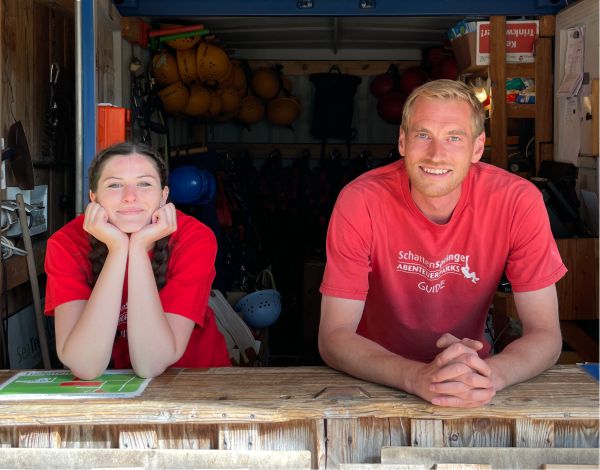 PraktikantIn AP Personal Zwei Mitarbeiter stehen im Empfangsraum und lächeln in die Kamera