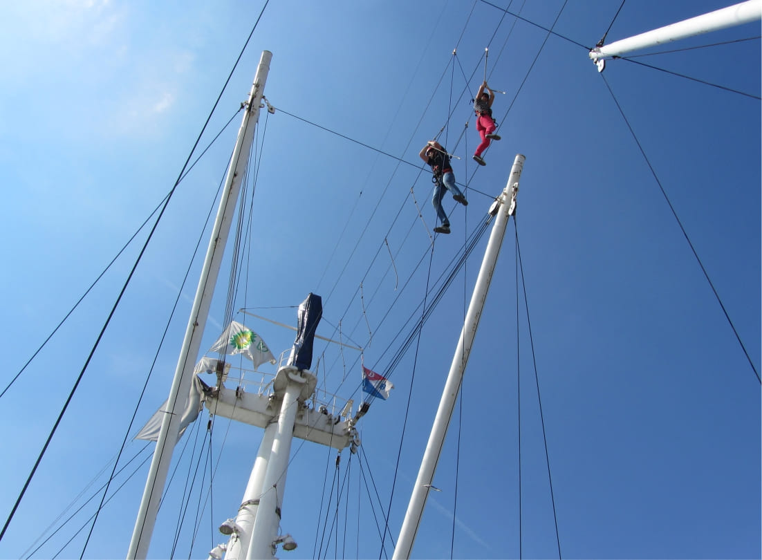 Blick von unten die Kletteranlage des Kletterschiffs Cap San Diego, zwei Kletterer balancieren auf dnnen Seilen
