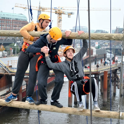 Drei Jugendliche helfen sich in groer Hhe bei der Bewltigung eines Balancierelements