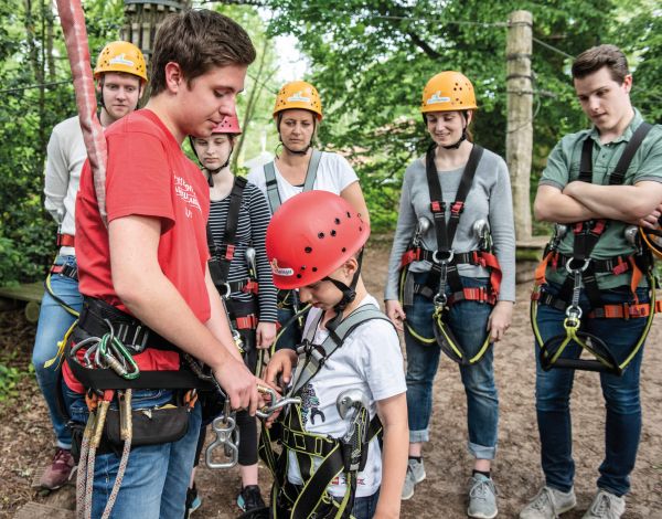 Guide PirateRock Ein Mitarbeiter prüft den Sitz der Kletterausrüstung bei einem Kind
